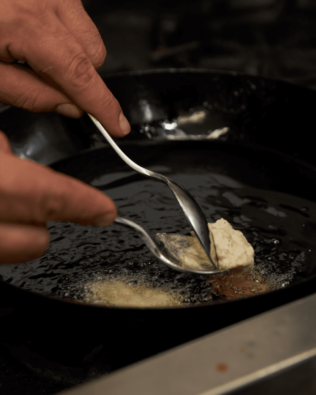 Fritelle di baccala batter being cooked in a pan